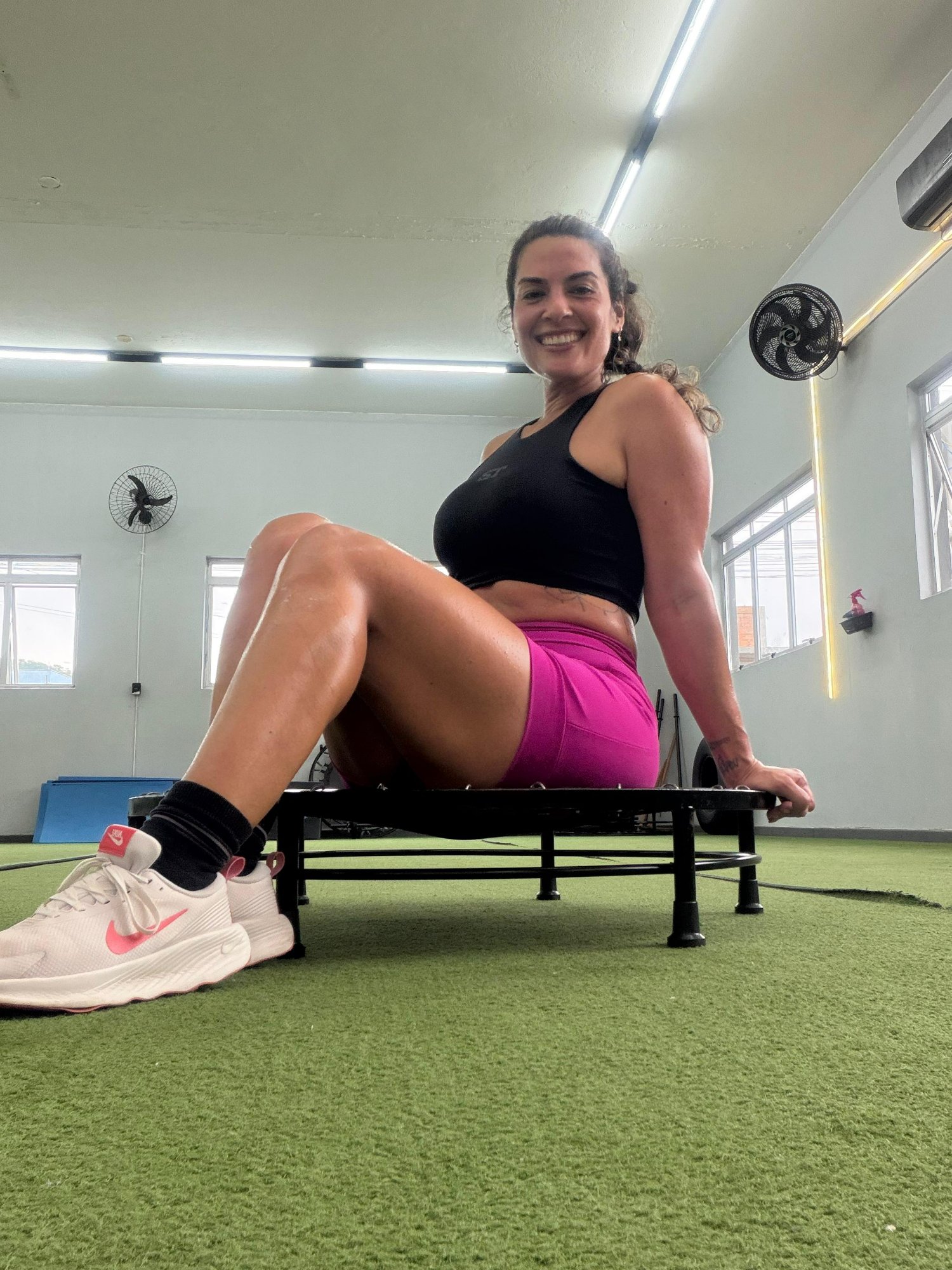 Pri sentada no trampolim, sorrindo. Momento de pausa no estúdio